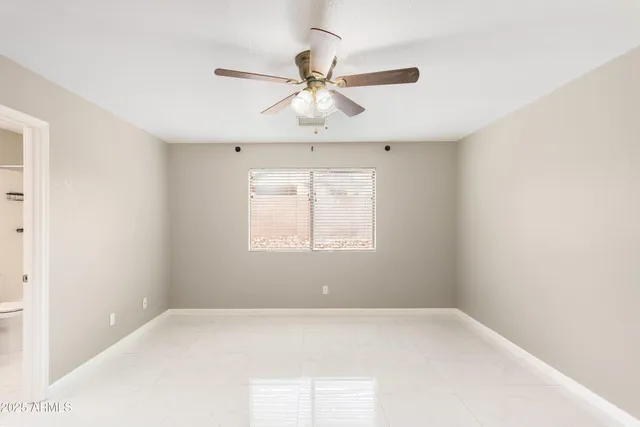 an empty room with a window and a fan