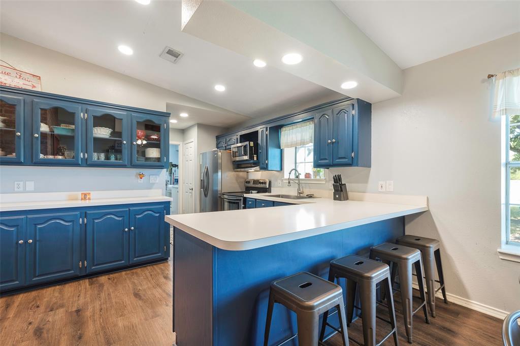 8229 East Lone Oak Road Valley View, TX 76272 - Photo 4 of 22 a large kitchen with stainless steel appliances sink cabinets and wooden floor
