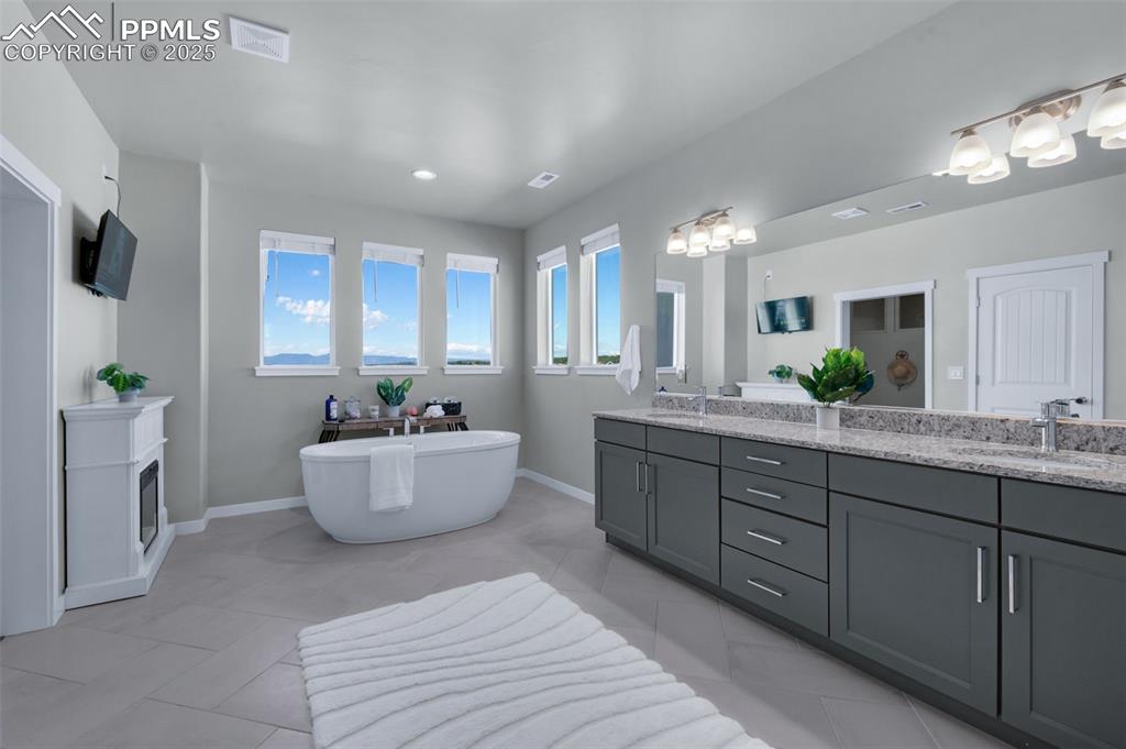 9755 Owl Perch Loop Colorado Springs, CO 80908 - Photo 23 of 50 a spacious bathroom with a double vanity sink a large mirror and a bathtub