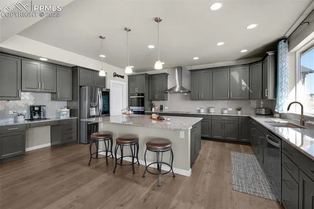 a kitchen with stainless steel appliances granite countertop a table chairs sink refrigerator and cabinets