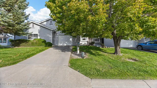 a view of a house with a small yard and a large tree