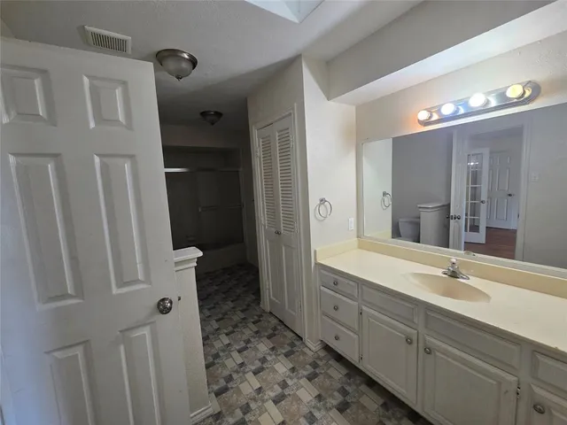 a spacious bathroom with a double vanity sink a toilet and a shower