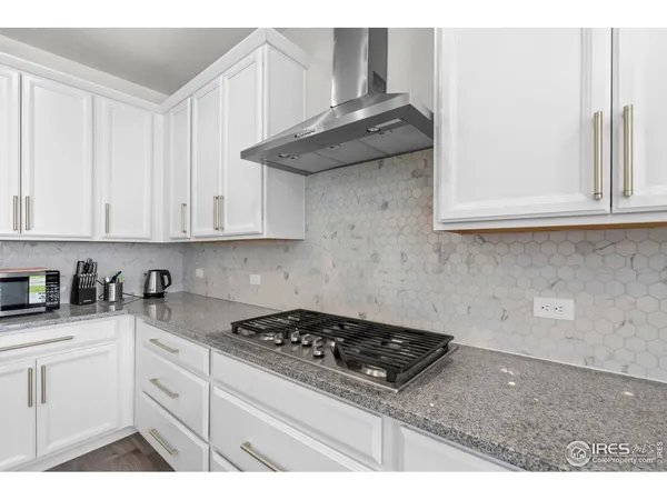 a kitchen with stainless steel appliances granite countertop a stove a white cabinet and a granite countertops with wooden floor