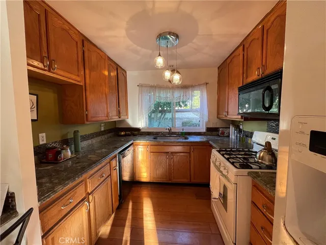 a kitchen with stainless steel appliances granite countertop a sink a stove top oven a counter space and cabinets