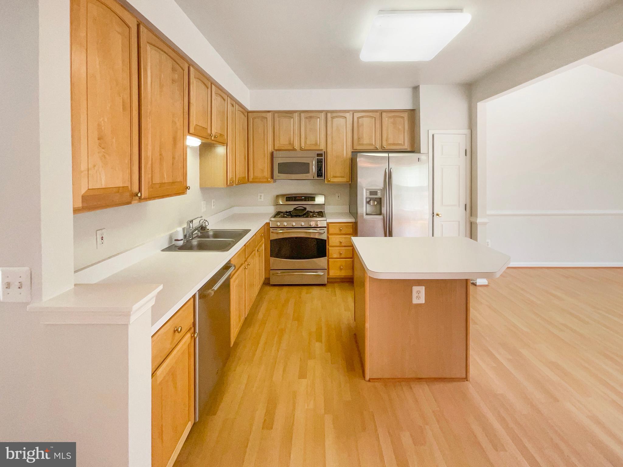 14272 Glade Spring Drive Centreville, VA 20121 - Photo 6 of 46 a kitchen with wooden floor and stainless steel appliances