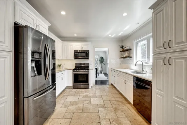 a large kitchen with cabinets a sink and stainless steel appliances