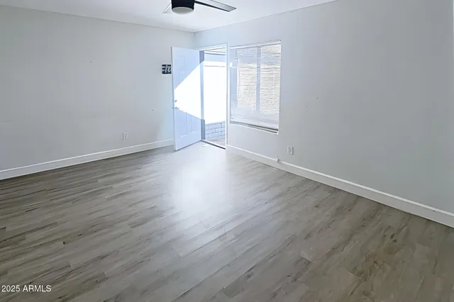 an empty room with wooden floor and a ceiling fan