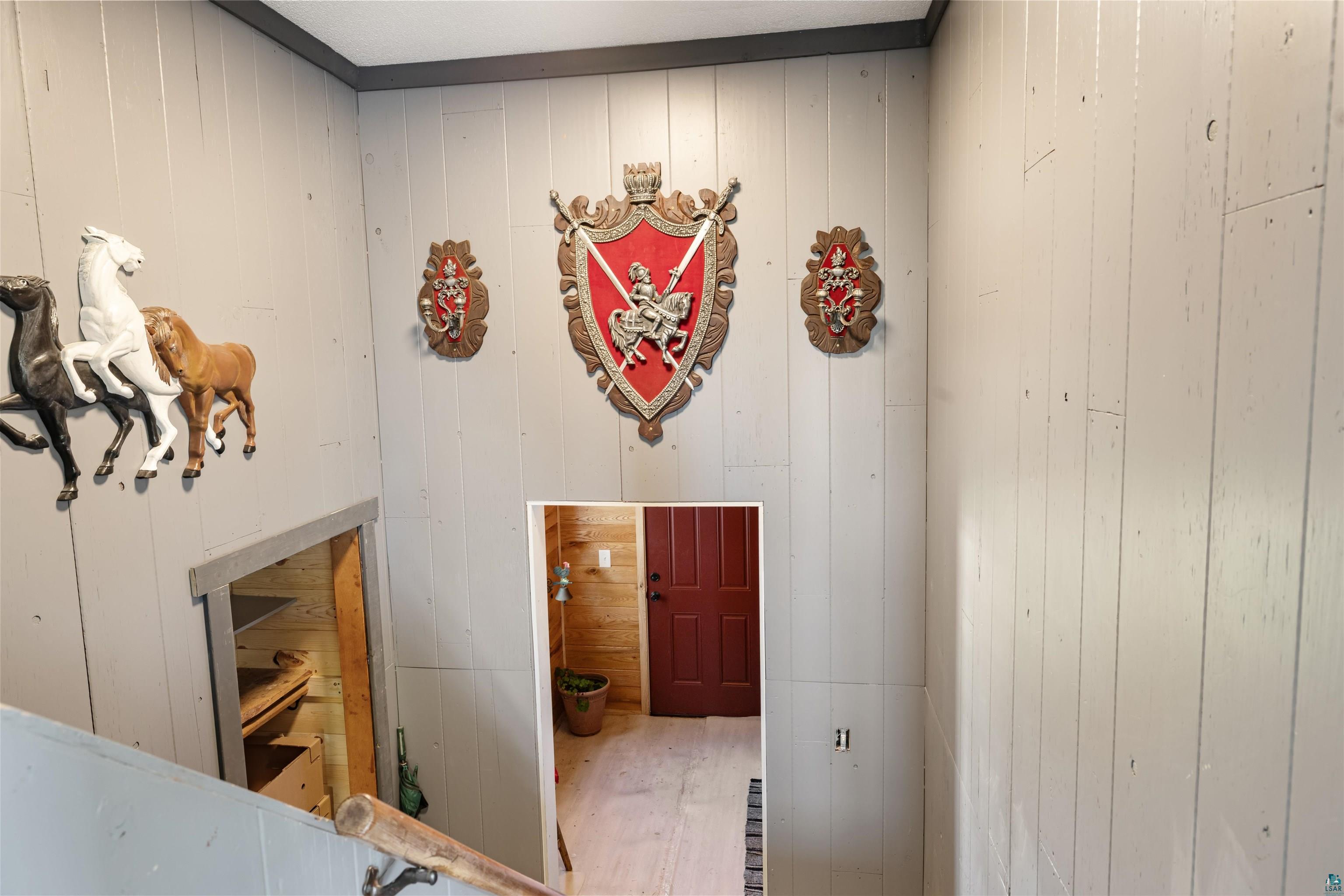 40139 County Road 251 Cohasset, MN 55721 - Photo 12 of 50 Staircase leading to lower level and entry / foyer with vertical wood paneling with dark trim, featuring a red paneled door at the lower level, and a wood handrail