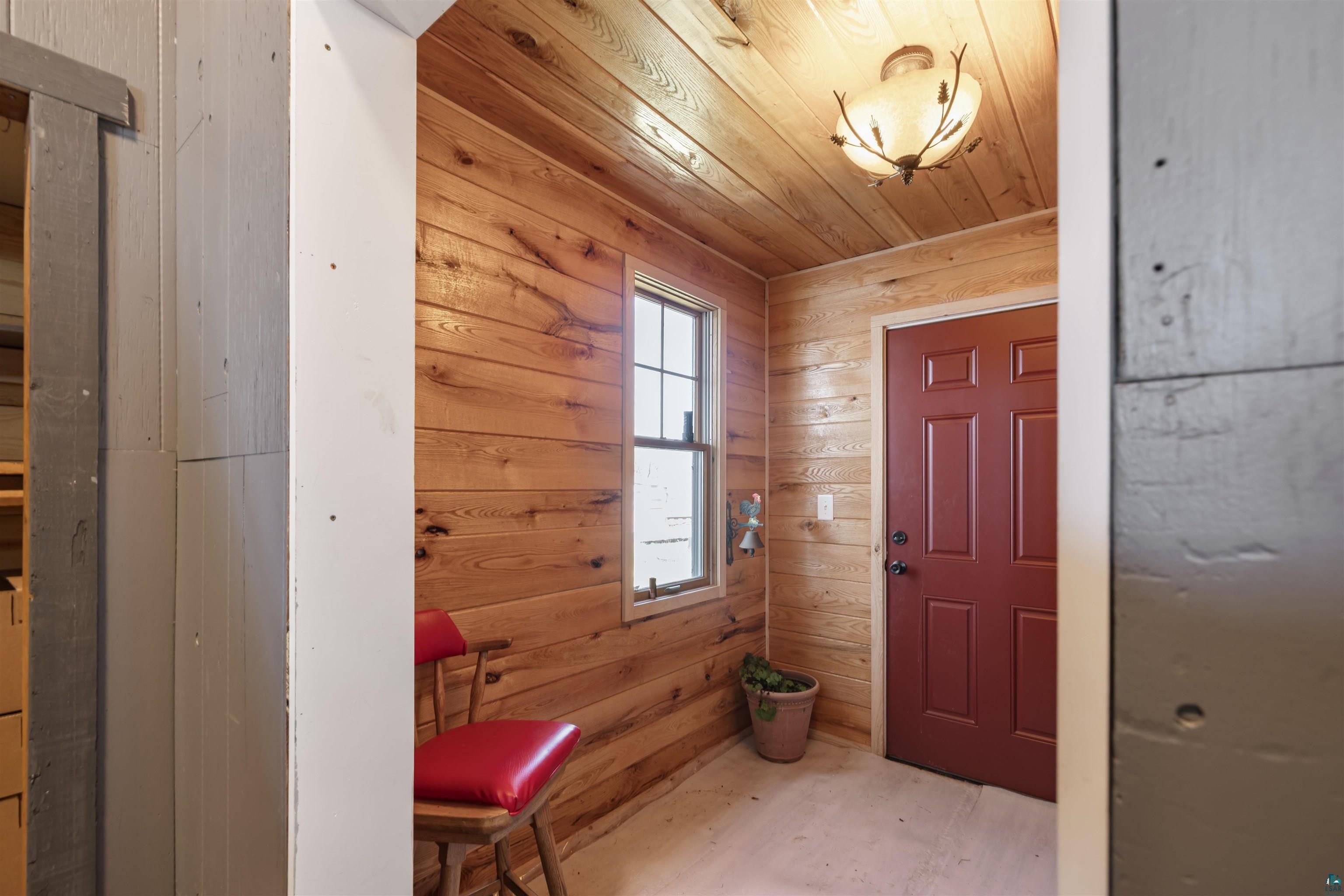 40139 County Road 251 Cohasset, MN 55721 - Photo 13 of 50 Natural wood-plank walls frame a classic red panel door and a double-hung window with a light wood frame