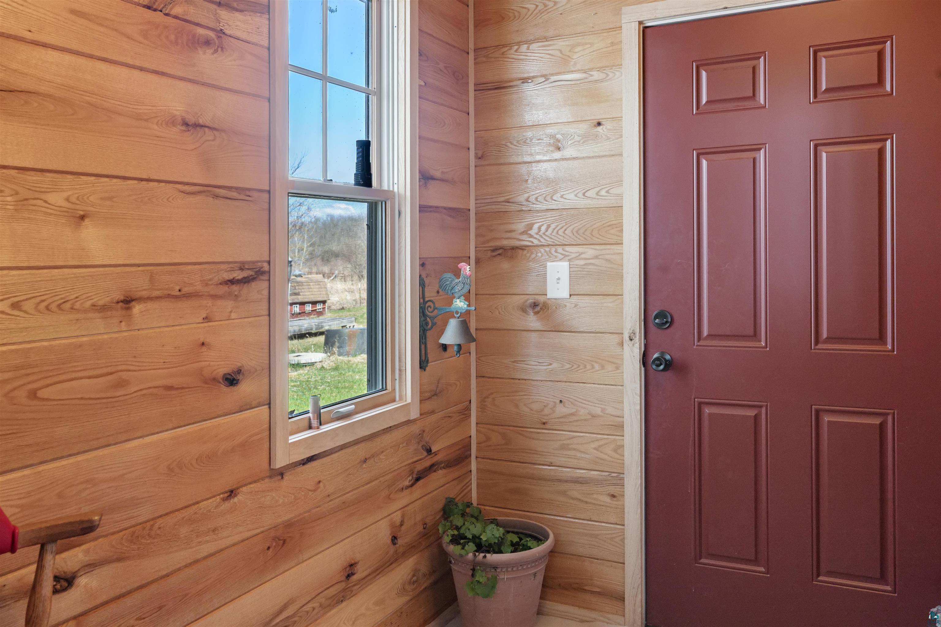 40139 County Road 251 Cohasset, MN 55721 - Photo 14 of 50 Natural wood-plank walls frame a classic red panel door and a double-hung window with a light wood frame