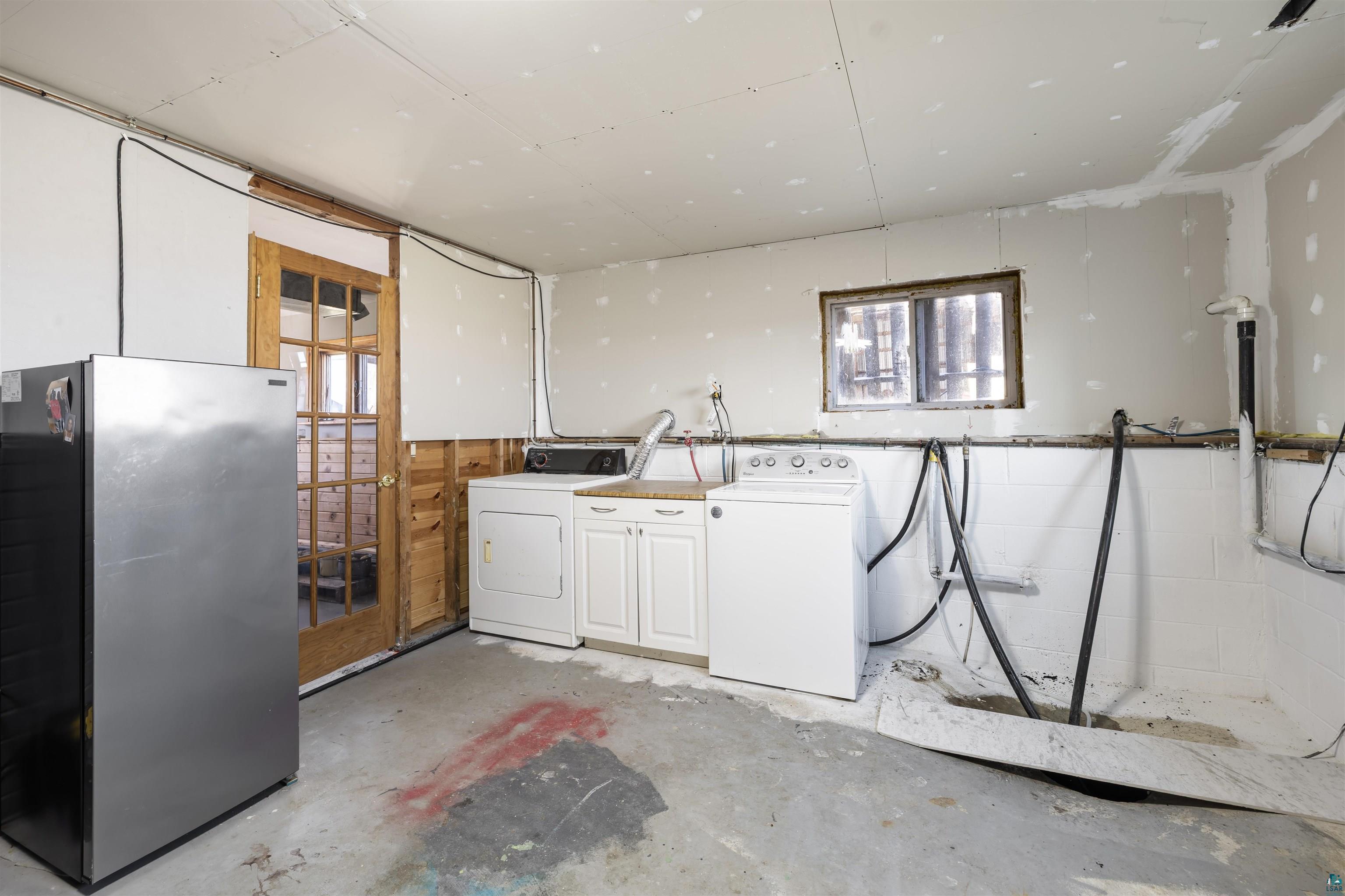 40139 County Road 251 Cohasset, MN 55721 - Photo 25 of 50 Utility area featuring a wood-frame door, compact window, built-in cabinetry, and concrete flooring