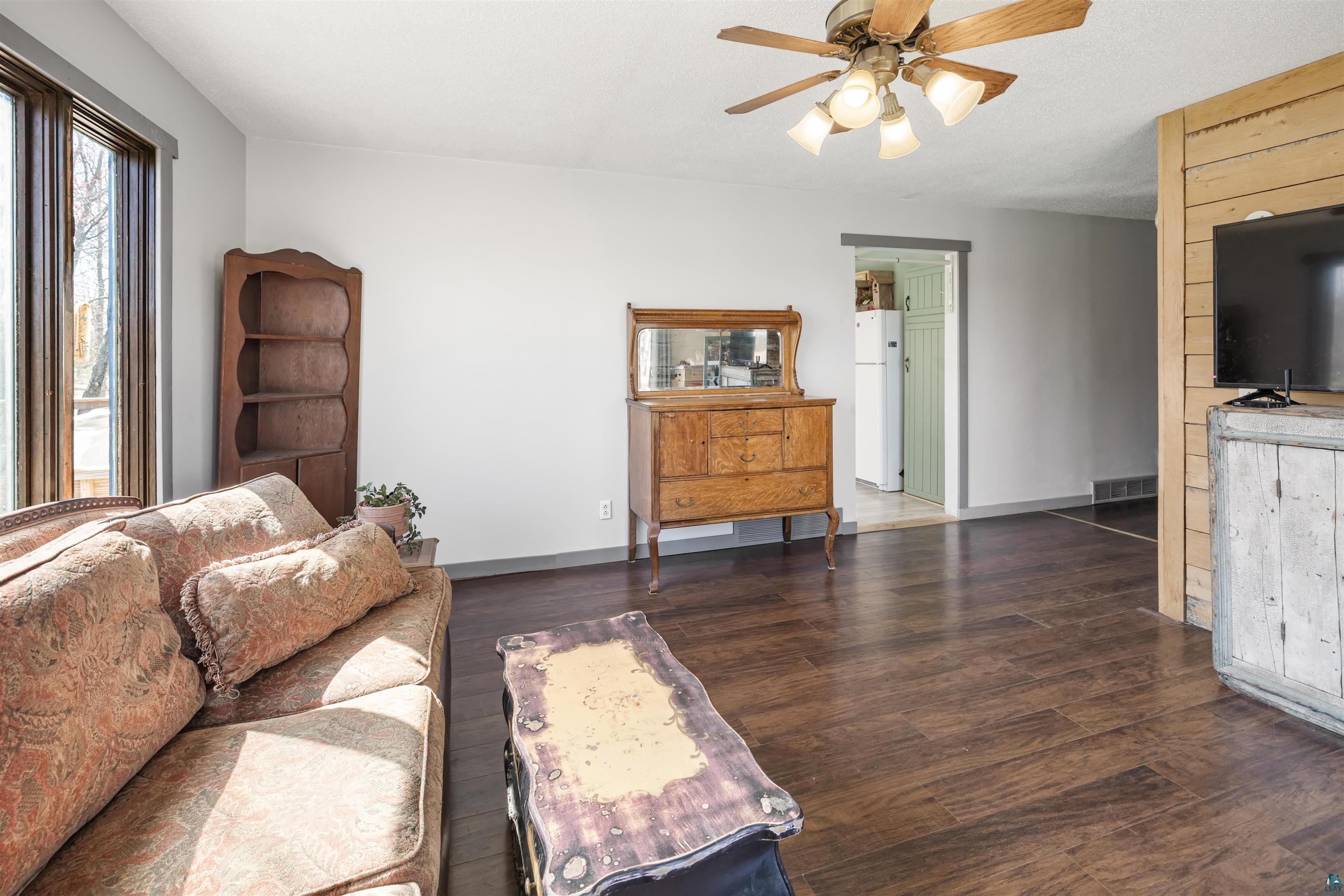 40139 County Road 251 Cohasset, MN 55721 - Photo 3 of 50 Spacious living area featuring laminate flooring, a ceiling fan with integrated lighting, and a large window providing ample natural light