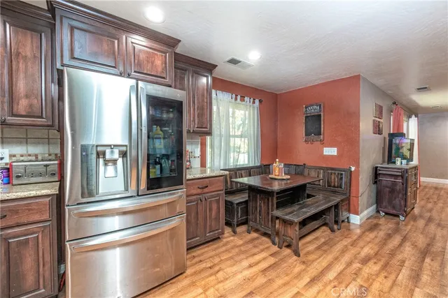 a living room with stainless steel appliances granite countertop a refrigerator a stove and a dining table with wooden floor