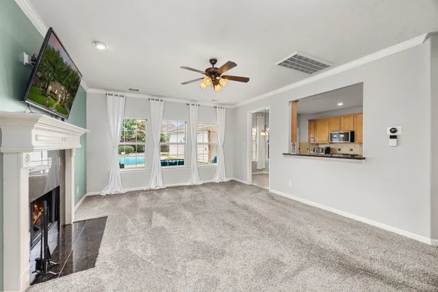 a view of a livingroom with a fireplace a chandelier fan and wooden floor