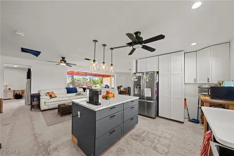 a large living room with stainless steel appliances kitchen island granite countertop furniture and a couch