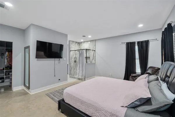 a bedroom with a bed tv and a large window