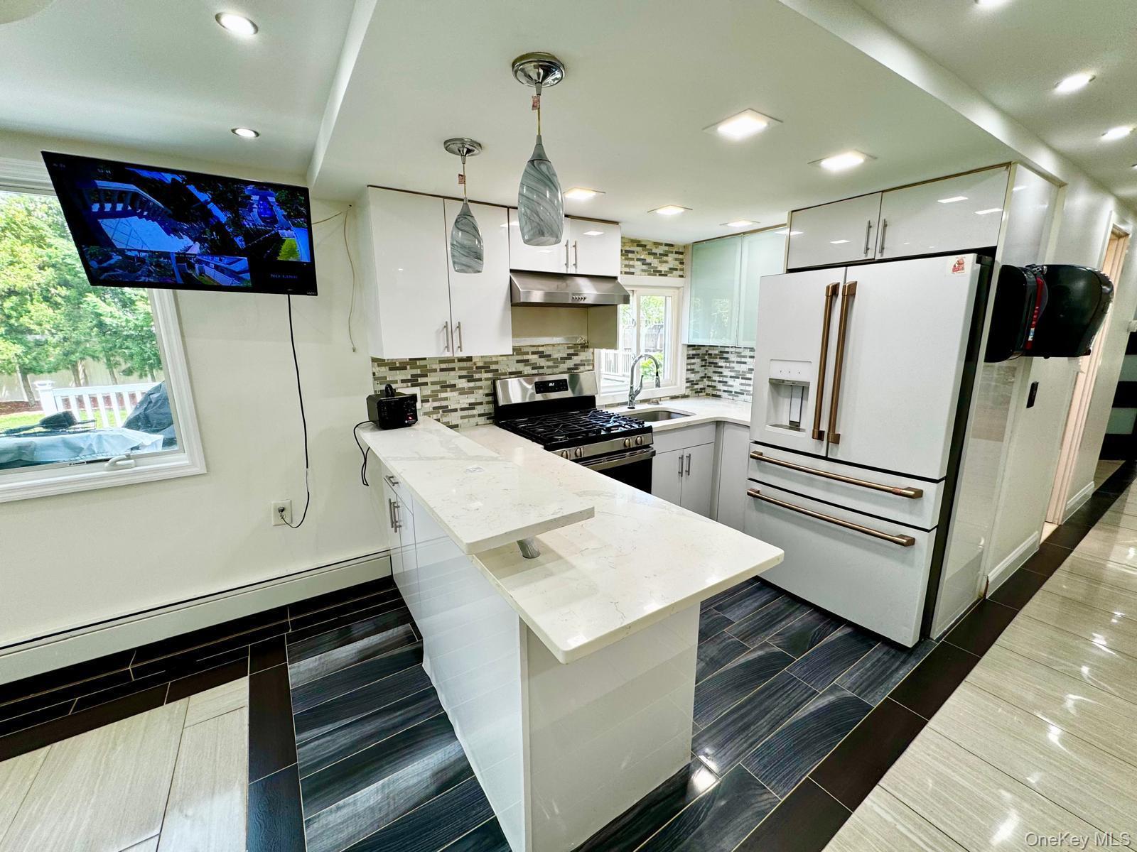 62 Walnut Road Inwood, NY 11096 - Photo 16 of 27 a kitchen with sink a refrigerator and chairs