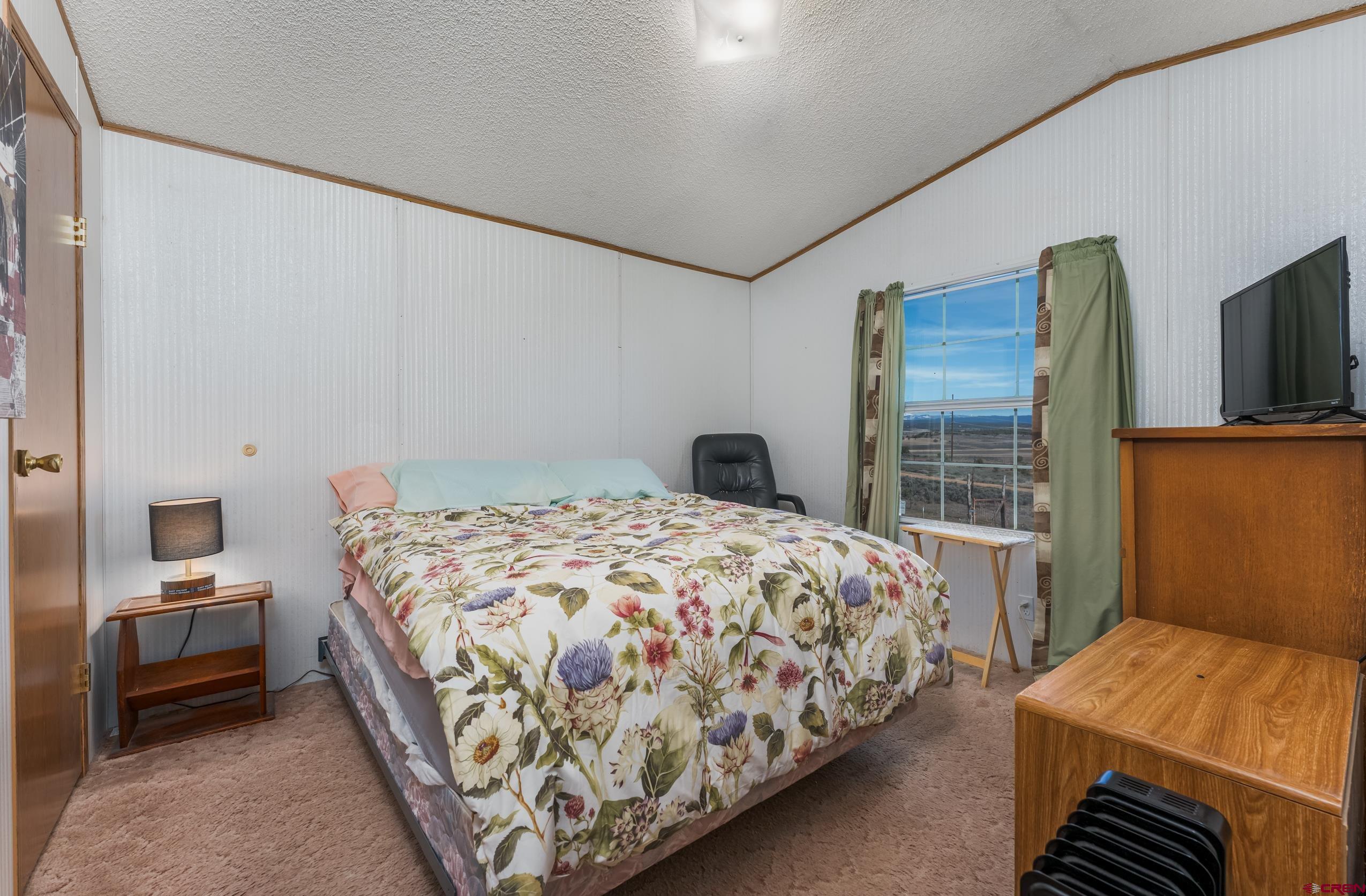 1837 Anna Road Ignacio, CO 81137 - Photo 26 of 32 a bedroom with a bed and flat tv screen next to a window