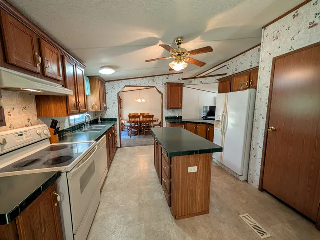 a kitchen with stainless steel appliances granite countertop a refrigerator a stove and a sink
