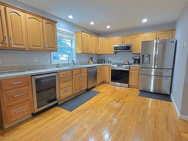 a kitchen with stainless steel appliances granite countertop a refrigerator a stove top oven a sink and dishwasher with wooden floor