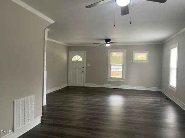 an empty room with wooden floor and windows