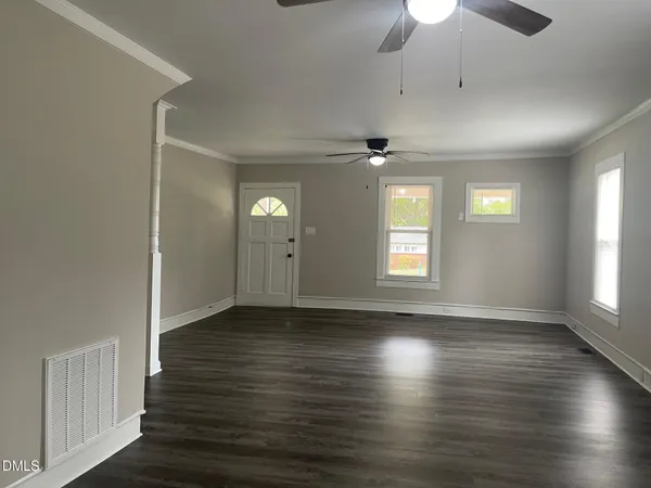 an empty room with wooden floor and windows