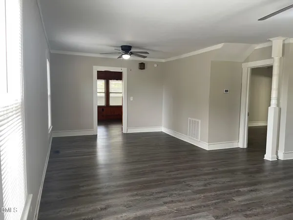 an empty room with wooden floor and windows