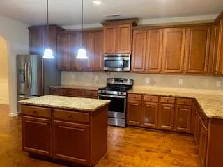 a kitchen with stainless steel appliances granite countertop wooden cabinets a stove top oven a sink and dishwasher