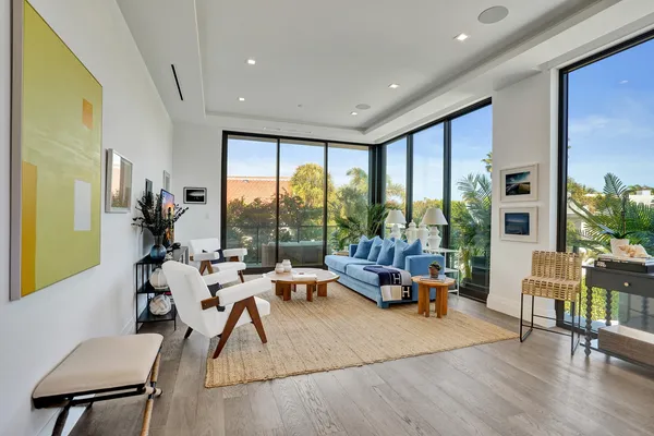 a living room with furniture large windows and wooden floor
