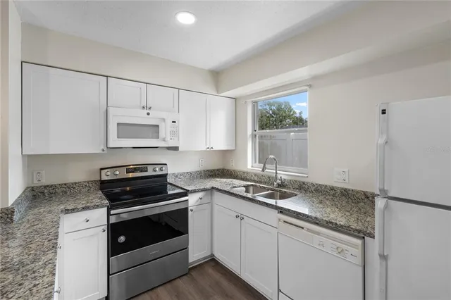a kitchen with granite countertop white cabinets and white appliances