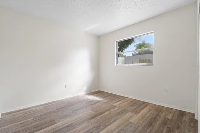 an empty room with wooden floor and window