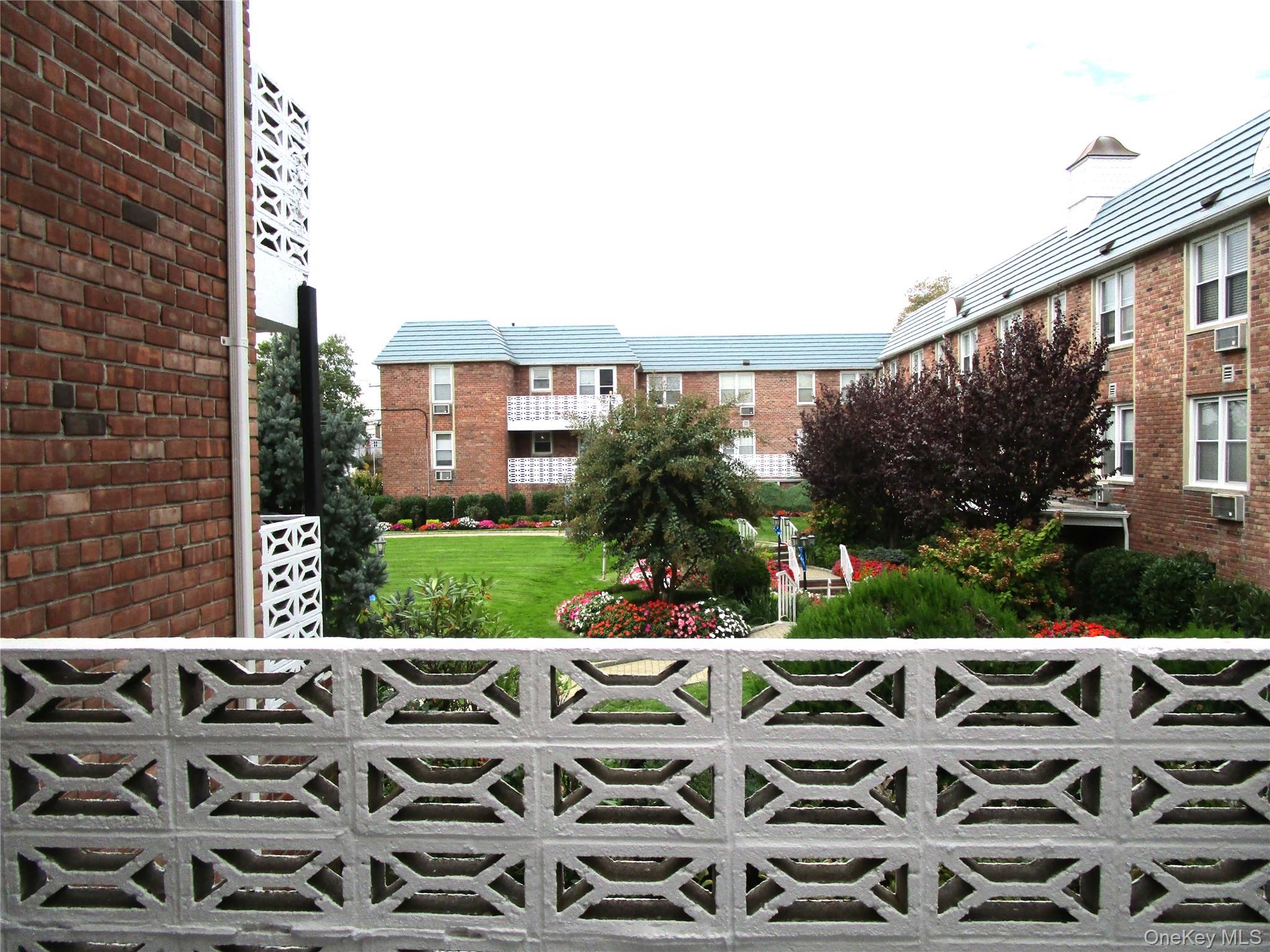 75 Noble Street, Unit 126 Lynbrook, NY 11563 - Photo 20 of 36 a view of a patio with table and chairs potted plants and large tree