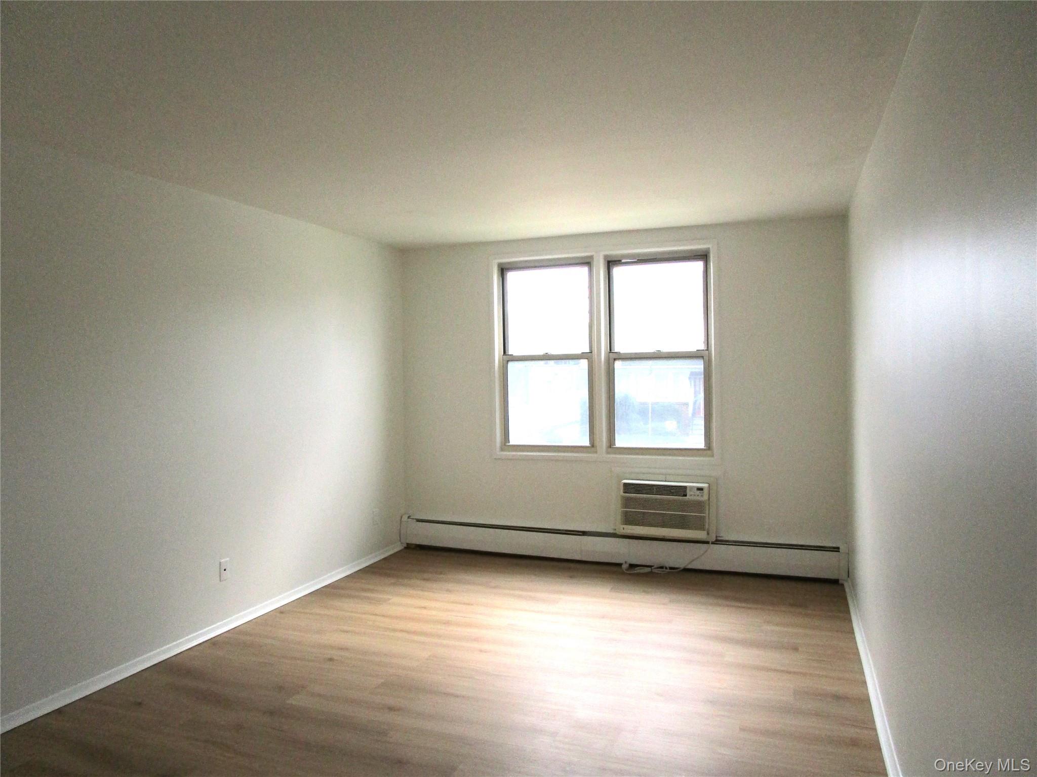 75 Noble Street, Unit 126 Lynbrook, NY 11563 - Photo 25 of 36 an empty room with wooden floor and windows