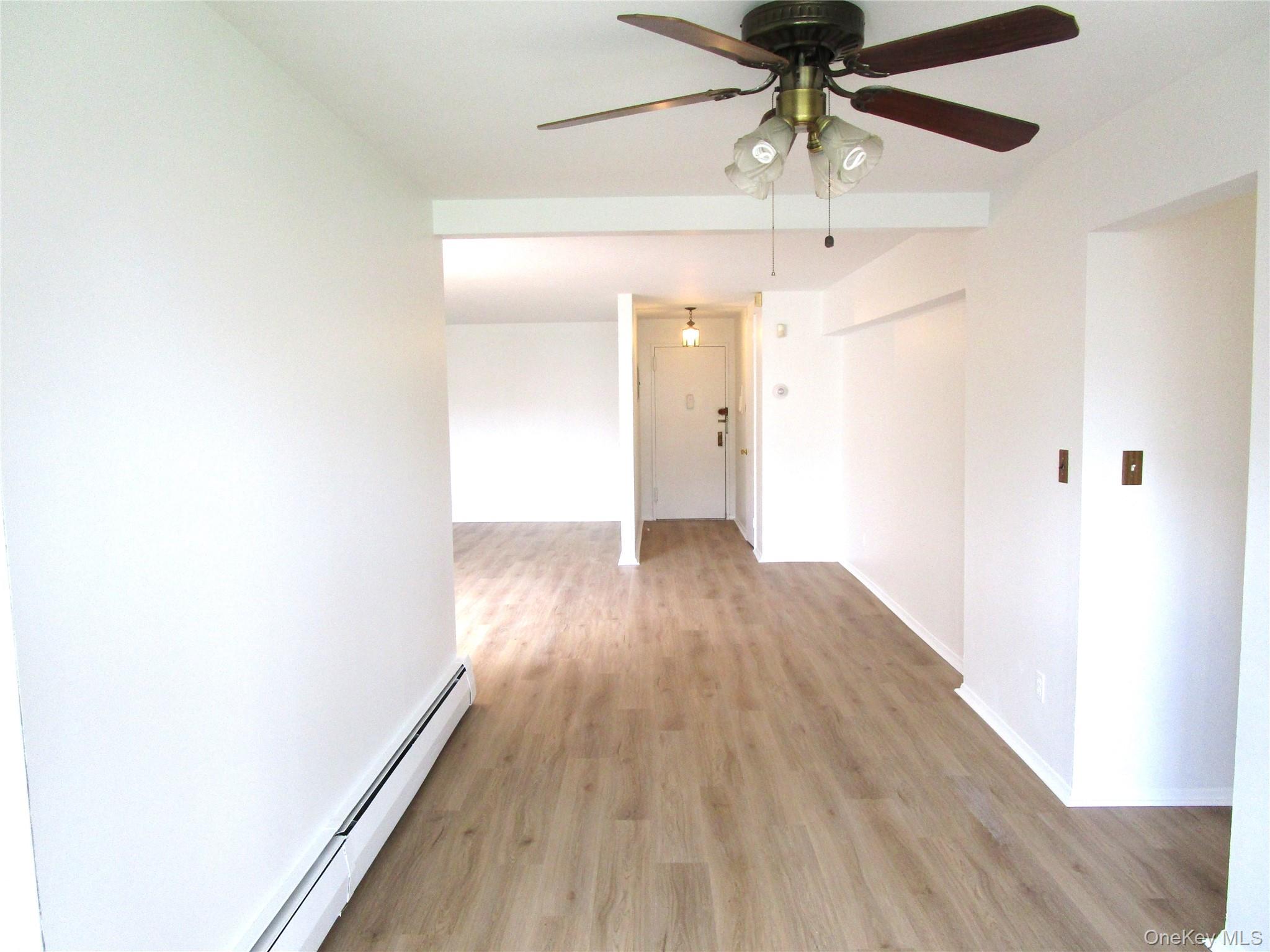 75 Noble Street, Unit 126 Lynbrook, NY 11563 - Photo 8 of 36 a view of a hallway with wooden floor and chandelier