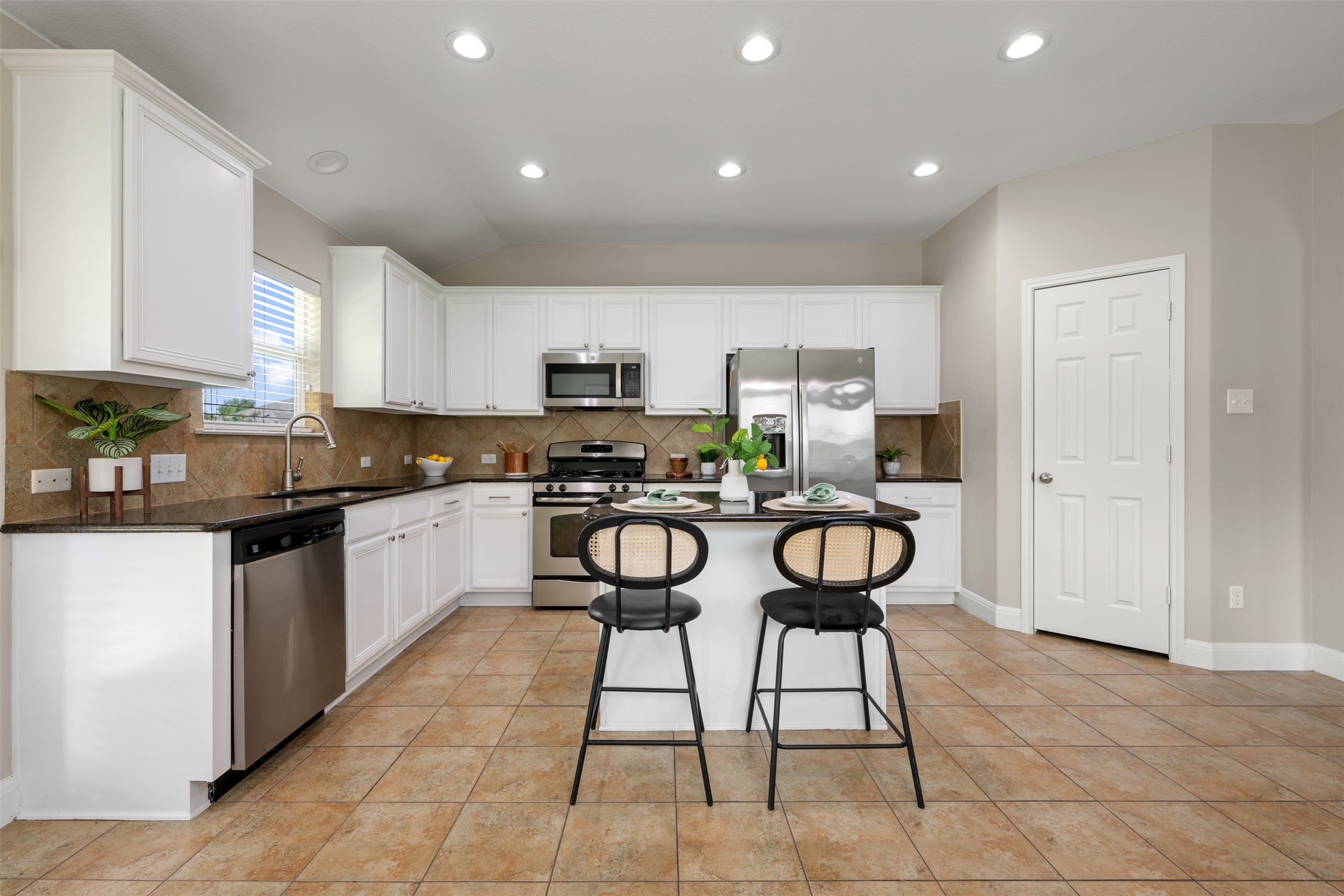 18820 Edinburgh Castle Road Pflugerville, TX 78660 - Photo 16 of 37 a kitchen with stainless steel appliances kitchen island granite countertop a stove a sink and a refrigerator