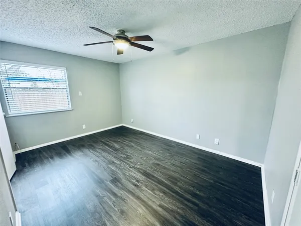 an empty room with wooden floor fan and windows