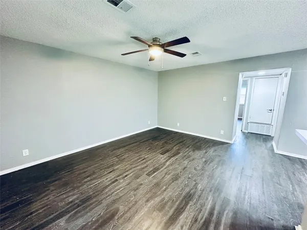 an empty room with wooden floor a ceiling fan and windows