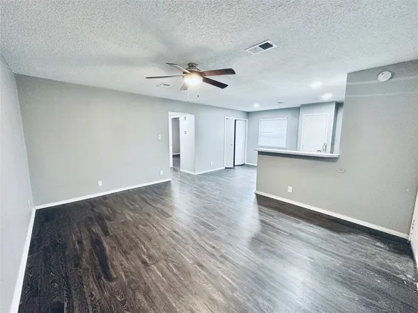 a view of an empty room with a window and wooden floor