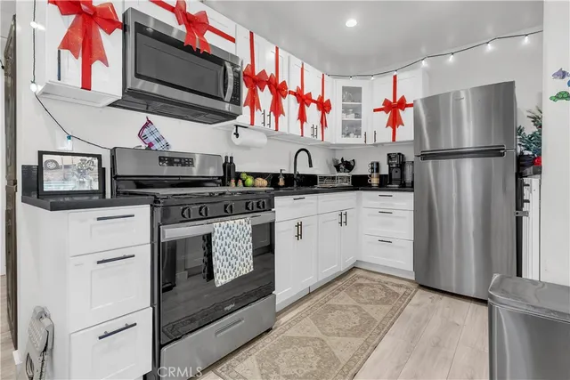 a kitchen with stainless steel appliances granite countertop a refrigerator sink stove and white cabinets