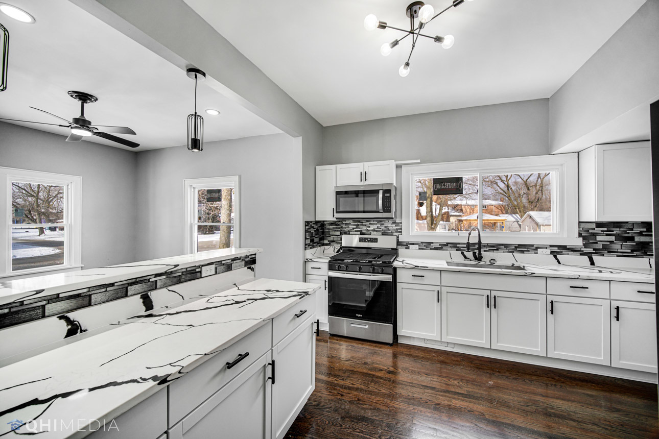 14601 Des Plaines Street Harvey, IL 60426 - Photo 6 of 21 a large white kitchen with stainless steel appliances granite countertop a stove and white cabinets