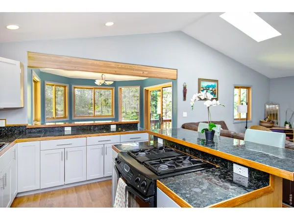 a kitchen with stainless steel appliances granite countertop a stove a sink and a granite counter tops with white cabinets