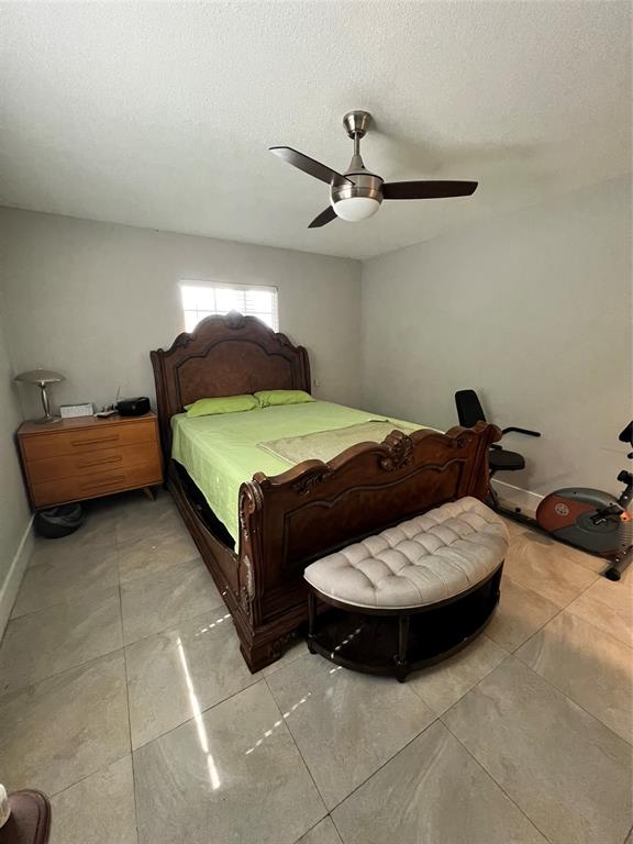 1410 Northeast 56th Court, Unit 1410 Fort Lauderdale, FL 33334 - Photo 12 of 14 a bedroom with a bed and ceiling fan