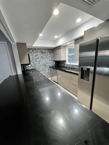 a kitchen with stainless steel appliances a refrigerator a sink a stove and chairs