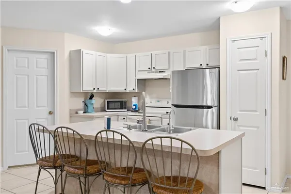 a kitchen with stainless steel appliances a dining table chairs and a refrigerator