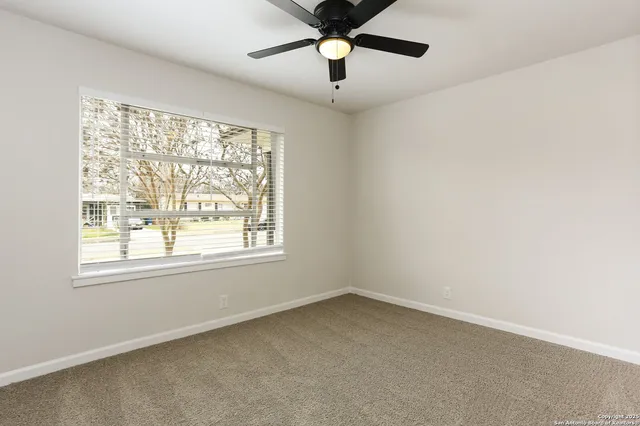 an empty room with a window and a fan