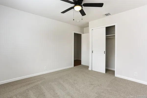 an empty room with closet and fan