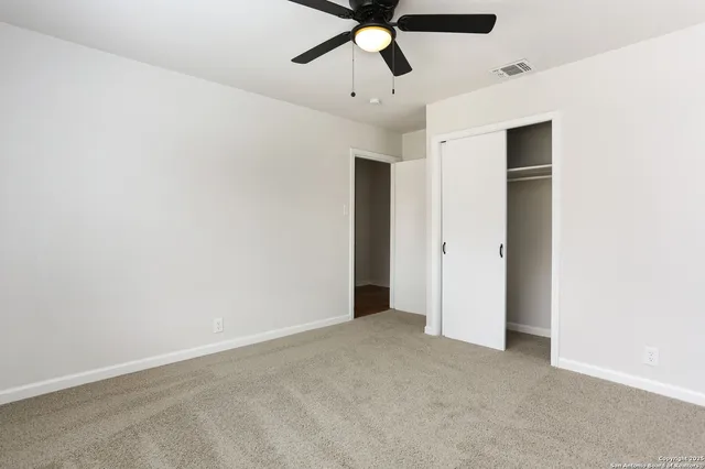 an empty room with closet and fan