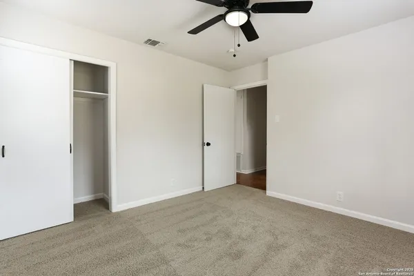 an empty room with a ceiling fan and carpet