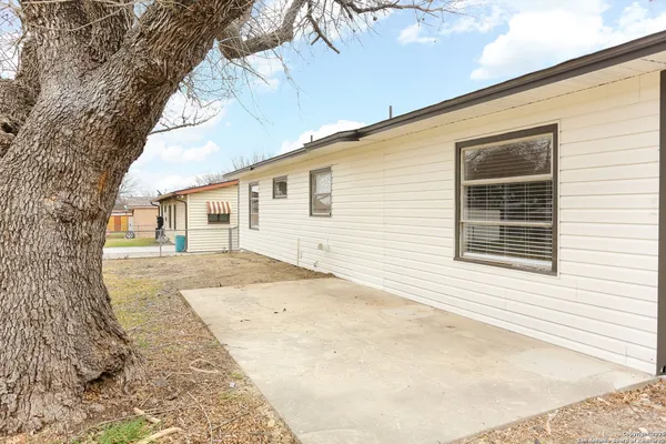 a view of a white house with a large tree