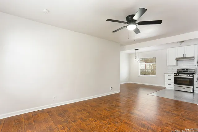 a view of an empty room with window and wooden floor